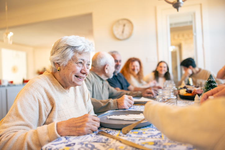 Senior woman smiling at a large family gathered around a dining table