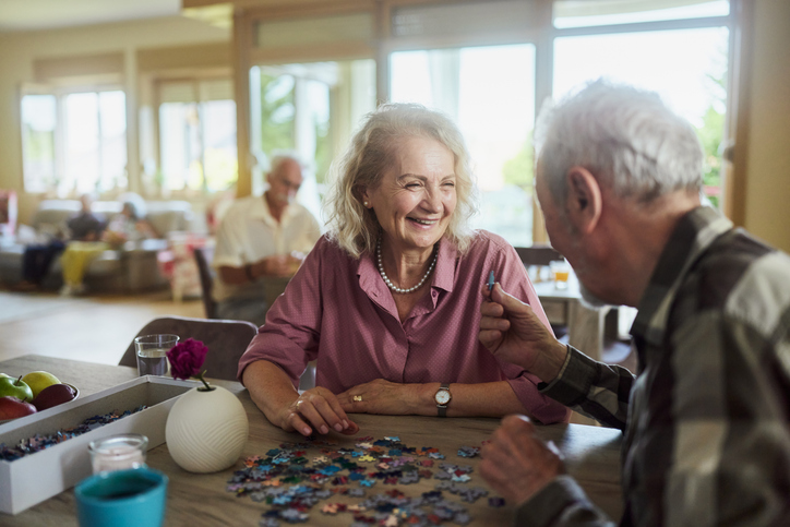Senior woman talking to her husband while working on a puzzle
