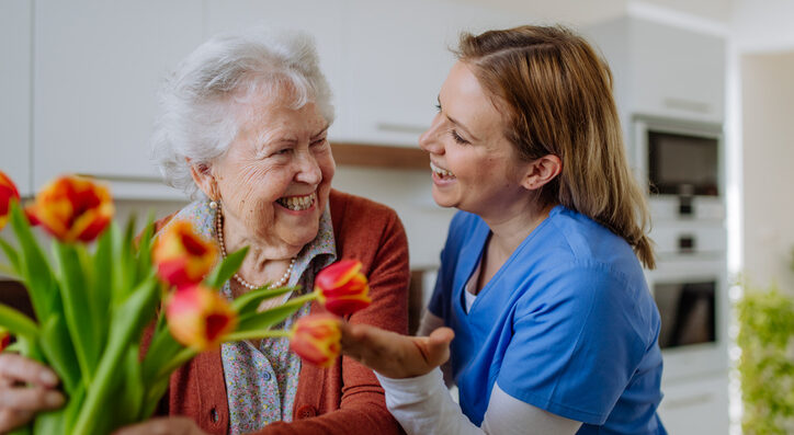 Senior woman and nurse with a tulip bouquet.