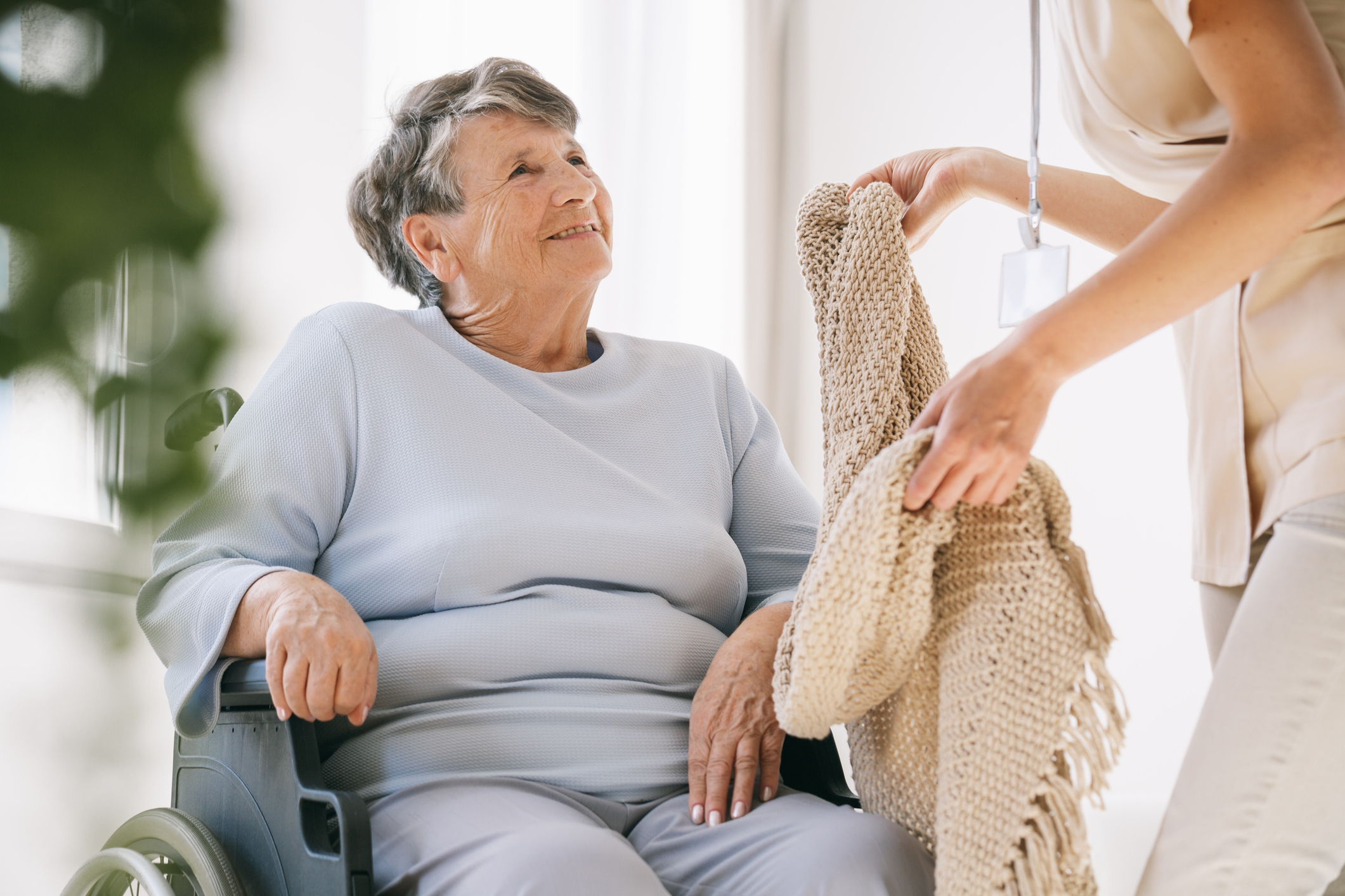 Caregiver giving a blanket to a senior woman