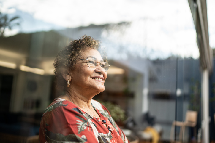 Senior woman looking out a window and smiling