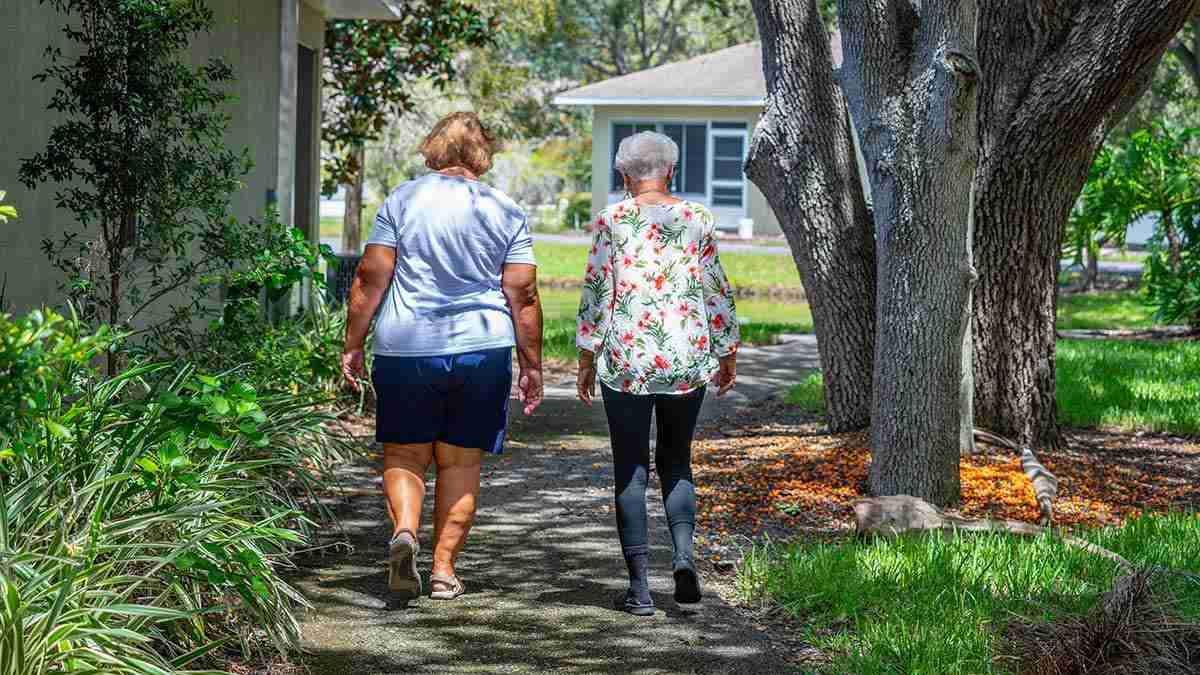 Two residents walking on a shaded nature path